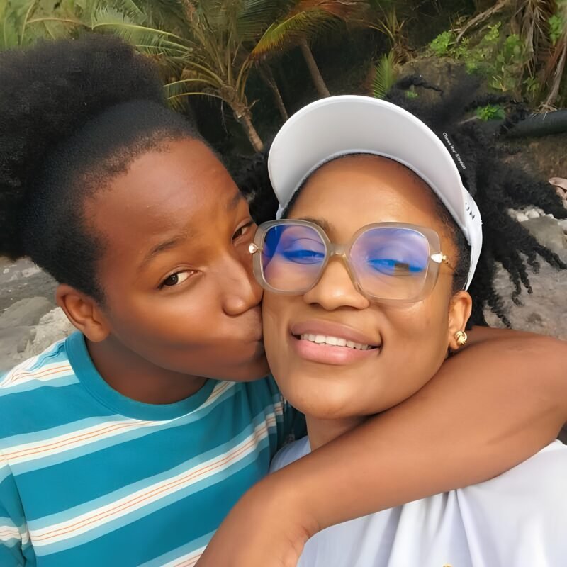 Teenage son embracing and kissing his mother on the cheek as they smile, symbolizing love, joy, and the deep bond between parent and child.
